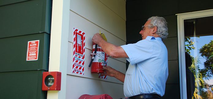 General Fire Employee Installing A Fire Extinguisher