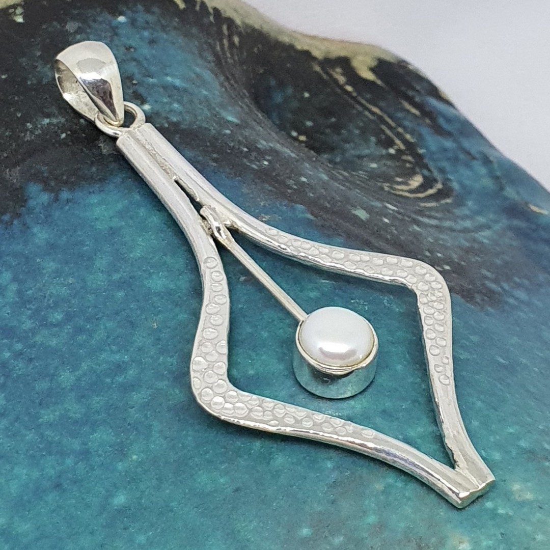 Open kite shaped patterned silver pendant with white pearl image 0