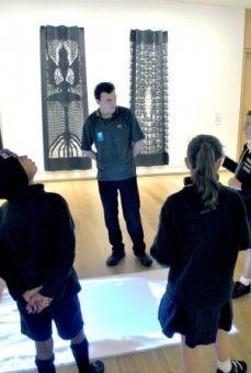 Tom Jaegar talks to students about a moving image projected onto the floor