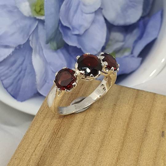 Silver ring with three sparkling red gemstones